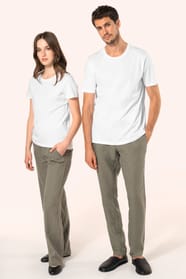 Jeune femme aux cheveux châtains longs et légèrement ondulés et jeune homme aux cheveux châtains courts portent un T-shirt blanc en coton Supima® col rond à manches courtes, 180 g/m². Associé à un pantalon en lin vert kaki clair, l’ensemble met en valeur 