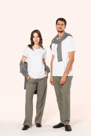 Jeune femme aux cheveux châtains longs et légèrement ondulés et jeune homme aux cheveux châtains courts portent un T-shirt blanc en coton Supima® col rond à manches courtes, 180 g/m². Associé à un pantalon en lin vert kaki clair, l’ensemble met en valeur 
