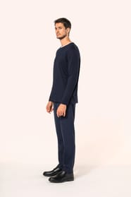 Jeune homme aux cheveux châtains courts portant un T-shirt bleu marine à manches longues en coton Supima® col rond, coupe droite, 180 g/m². Sa fibre extra-longue apporte résistance et douceur, tandis que les finitions soignées et la construction coupée-co