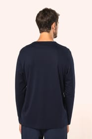Jeune homme aux cheveux châtains courts portant un T-shirt bleu marine à manches longues en coton Supima® col rond, coupe droite, 180 g/m². Sa fibre extra-longue apporte résistance et douceur, tandis que les finitions soignées et la construction coupée-co