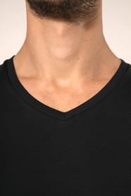 Jeune homme aux cheveux châtains courts portant un T-shirt noir à manches courtes en coton Supima® col V, coupe droite, 180 g/m². Sa fibre extra-longue apporte résistance et douceur, tandis que les finitions soignées et la construction coupée-cousue souli