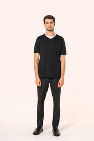Jeune homme aux cheveux châtains courts portant un T-shirt noir à manches courtes en coton Supima® col V, coupe droite, 180 g/m². Sa fibre extra-longue apporte résistance et douceur, tandis que les finitions soignées et la construction coupée-cousue souli