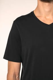 Jeune homme aux cheveux châtains courts portant un T-shirt noir à manches courtes en coton Supima® col V, coupe droite, 180 g/m². Sa fibre extra-longue apporte résistance et douceur, tandis que les finitions soignées et la construction coupée-cousue souli