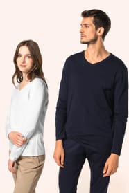 Jeune femme aux cheveux châtains longs et légèrement ondulés et jeune homme aux cheveux châtains courts portent chacun un T-shirt en coton Supima® col V, coupe droite, 180 g/m². La fibre extra-longue offre résistance et douceur, tandis que les finitions s