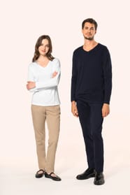 Jeune femme aux cheveux châtains longs et légèrement ondulés et jeune homme aux cheveux châtains courts portent chacun un T-shirt en coton Supima® col V, coupe droite, 180 g/m². La fibre extra-longue offre résistance et douceur, tandis que les finitions s