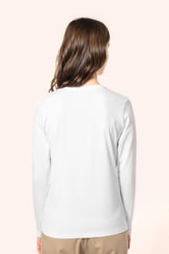 Jeune femme aux cheveux châtains longs et légèrement ondulés portant un T-shirt blanc à manches longues en coton Supima® col V, coupe droite, 180 g/m². Sa fibre extra-longue apporte résistance et douceur, tandis que les finitions soignées et la constructi