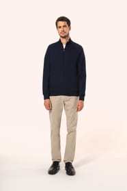 Jeune homme aux cheveux châtains courts portant une veste zippée bleu marine, coupe contemporaine et confortable, 320 g/m². Son tissu bénéficie du traitement LSI (Low Shrinkage Interlock) qui garantit un faible rétrécissement. Il complète sa tenue avec un