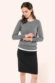 Jeune femme aux cheveux châtains attachés en demi-queue portant une jupe droite confectionnée dans un mélange de matières de qualité (50% polyester, 23% viscose, 22% laine, 5% élasthanne) avec doublure stretch 100% polyester. Son confort est renforcé par 