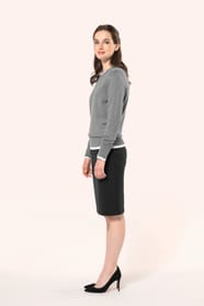 Jeune femme aux cheveux châtains attachés en demi-queue portant une jupe droite confectionnée dans un mélange de matières de qualité (50% polyester, 23% viscose, 22% laine, 5% élasthanne) avec doublure stretch 100% polyester. Son confort est renforcé par 