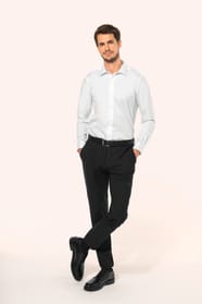 Jeune homme aux cheveux châtains courts portant une chemise blanche en twill à manches longues, confectionnée en coton double retors 80x2 de qualité supérieure. Sa coupe ajustée, structurée par deux pinces dans le dos, se distingue par des finitions raffi