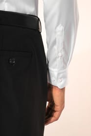Jeune homme aux cheveux châtains courts portant une chemise blanche en twill à manches longues, confectionnée en coton double retors 80x2 de qualité supérieure. Sa coupe ajustée, structurée par deux pinces dans le dos, se distingue par des finitions raffi