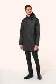 Jeune homme aux cheveux châtains courts portant une veste de pluie unisexe noire en tissu imperméable 5000 mm, dotée d’une capuche à visière et de coutures thermosoudées. Confectionnée avec une enduction polyuréthane à l’extérieur et une doublure polyeste