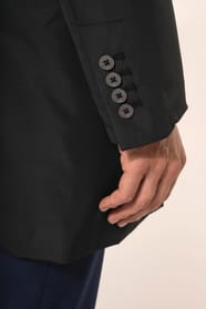Jeune homme aux cheveux châtains courts portant un trench structuré noir à col tailleur, alliant élégance et sobriété. Confectionné en polyester trois couches contrecollées, il associe technicité et confort grâce à un tissu imperméable 8000 mm et un rembo