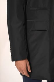 Jeune homme aux cheveux châtains courts portant un trench structuré noir à col tailleur, alliant élégance et sobriété. Confectionné en polyester trois couches contrecollées, il associe technicité et confort grâce à un tissu imperméable 8000 mm et un rembo