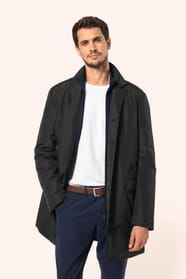 Jeune homme aux cheveux châtains courts portant un trench structuré noir à col tailleur, ouvert sur un T-shirt blanc rentré dans un pantalon de costume bleu, maintenu par une ceinture marron. Confectionné en polyester trois couches contrecollées, il assoc