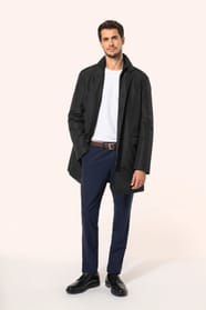 Jeune homme aux cheveux châtains courts portant un trench structuré noir à col tailleur, ouvert sur un T-shirt blanc rentré dans un pantalon de costume bleu, maintenu par une ceinture marron. Confectionné en polyester trois couches contrecollées, il assoc