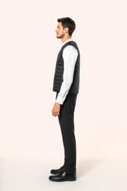 Jeune homme aux cheveux châtains courts portant un bodywarmer léger noir, conçu pour être porté seul ou sous une veste grâce à sa finesse. Réalisé en polyamide avec un rembourrage intérieur en Thinsulate™, il assure un maintien optimal de la chaleur tout 