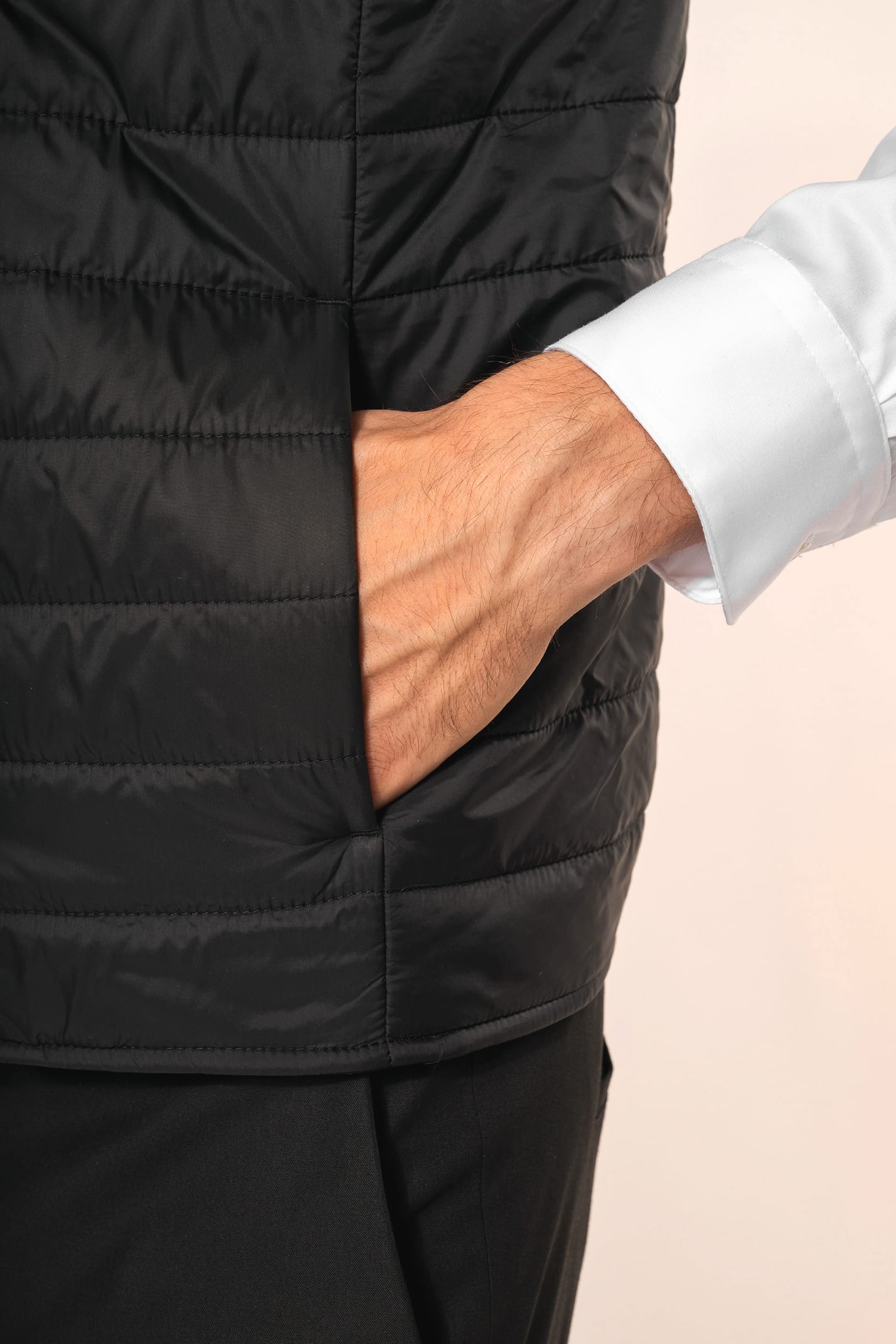 Jeune homme aux cheveux châtains courts portant un bodywarmer léger noir, conçu pour être porté seul ou sous une veste grâce à sa finesse. Réalisé en polyamide avec un rembourrage intérieur en Thinsulate™, il assure un maintien optimal de la chaleur tout 