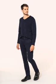 Jeune homme aux cheveux châtains courts portant un chino bleu profond à la coupe straight, moderne et tendance. Confectionné en coton et élasthanne, il associe confort, souplesse et résistance, idéal en toutes saisons. Il l’associe à un T-shirt col V bleu