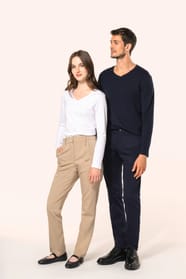 Jeune homme aux cheveux châtains courts et jeune femme aux cheveux châtains longs, détachés et légèrement ondulés, composent un duo élégant et moderne. Il porte un chino bleu profond à la coupe straight, associé à un T-shirt col V bleu assorti, alliant co