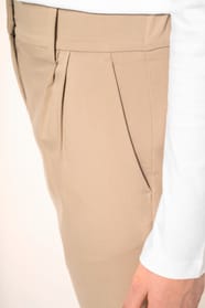 Jeune femme portant un pantalon sable en tissu twill, élégant et confortable, composé de viscose, associé à une chemise blanche intemporelle. Cet ensemble sobre et raffiné allie modernité et confort au quotidien.