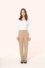 Jeune femme aux cheveux châtains longs, détachés et légèrement ondulés, portant un pantalon sable en tissu twill, élégant et confortable, composé de viscose, associé à une chemise blanche intemporelle. Cet ensemble sobre et raffiné allie modernité et conf