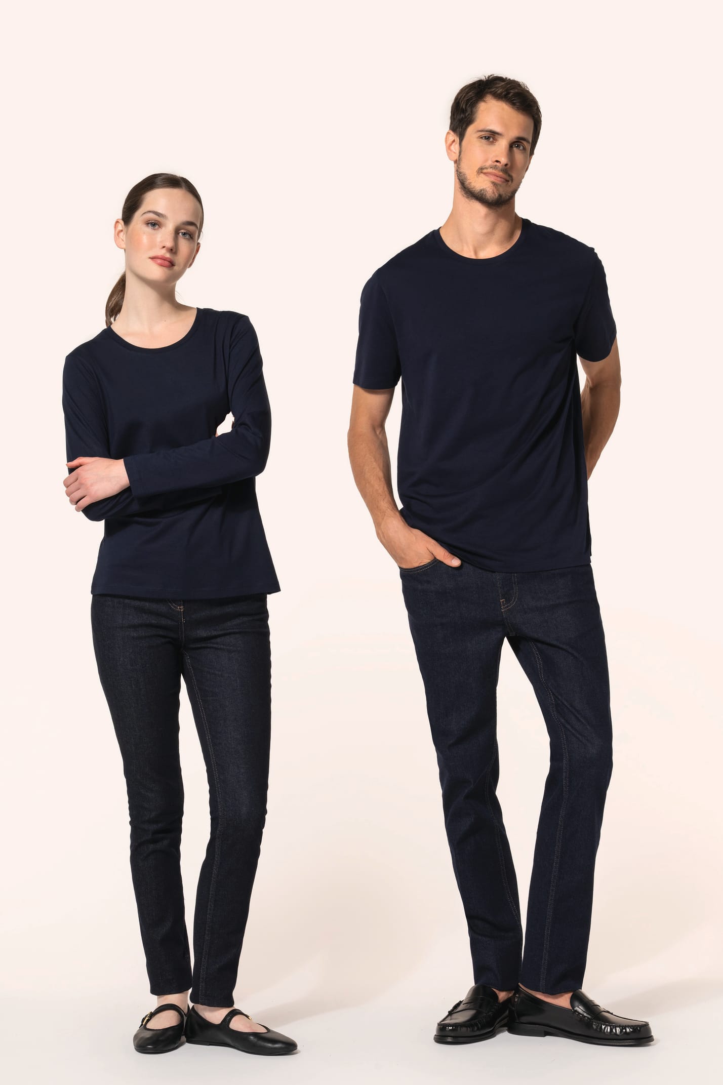 Jeune homme aux cheveux châtains courts et jeune femme aux cheveux châtains longs attachés portent chacun un jean ajusté en denim (99% coton, 1% élasthanne) à la coupe straight, confortable et moderne. Leurs finitions soignées incluent une mercerie et des