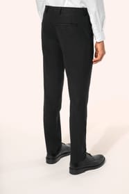 Homme portant un pantalon de costume noir à la coupe straight élégante, associé à une chemise blanche rentrée et une ceinture assortie. L’ensemble est complété par des chaussures de ville en cuir noir brillant, pour une silhouette sobre et sophistiquée.