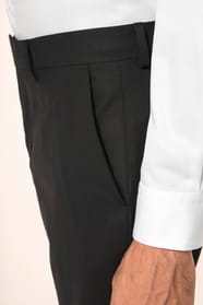 Homme portant un pantalon de costume noir à la coupe straight élégante, associé à une chemise blanche rentrée et une ceinture assortie. L’ensemble est complété par des chaussures de ville en cuir noir brillant, pour une silhouette sobre et sophistiquée.