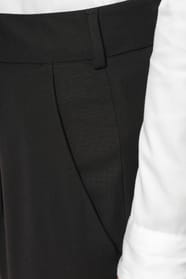 Jeune femme portant un pantalon City noir élégant, confectionné dans une matière de qualité offrant confort et tenue impeccable. Elle l’associe à une chemise blanche et à des escarpins noirs pour une silhouette raffinée et intemporelle.