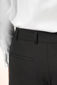 Jeune femme portant un pantalon City noir élégant, confectionné dans une matière de qualité offrant confort et tenue impeccable. Elle l’associe à une chemise blanche et à des escarpins noirs pour une silhouette raffinée et intemporelle.