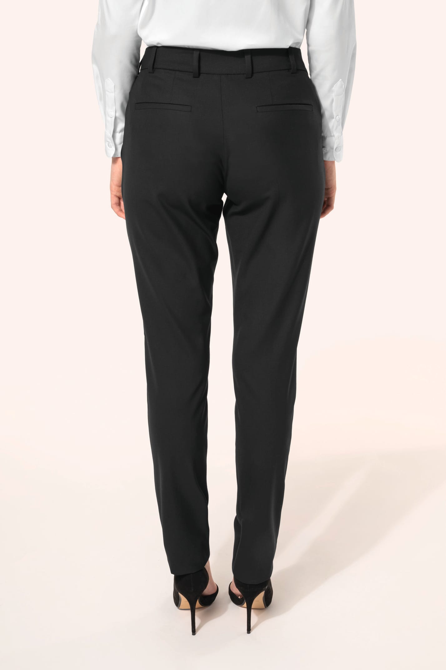 Jeune femme portant un pantalon City noir élégant, confectionné dans une matière de qualité offrant confort et tenue impeccable. Elle l’associe à une chemise blanche et à des escarpins noirs pour une silhouette raffinée et intemporelle.