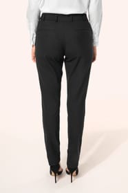 Jeune femme portant un pantalon City noir élégant, confectionné dans une matière de qualité offrant confort et tenue impeccable. Elle l’associe à une chemise blanche et à des escarpins noirs pour une silhouette raffinée et intemporelle.