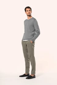 Jeune homme portant un pull gris clair chiné en coton Supima® col rond. Confectionné en fibres extra-longues, ce coton d’exception offre souplesse, douceur et durabilité. Sa maille révèle des points fantaisie obtenus par une technique de tricotage spécifi