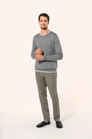 Jeune homme portant un pull gris clair chiné en coton Supima® col rond. Confectionné en fibres extra-longues, ce coton d’exception offre souplesse, douceur et durabilité. Sa maille révèle des points fantaisie obtenus par une technique de tricotage spécifi
