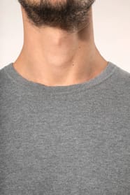 Jeune homme portant un pull gris clair chiné en coton Supima® col rond. Confectionné en fibres extra-longues, ce coton d’exception offre souplesse, douceur et durabilité. Sa maille révèle des points fantaisie obtenus par une technique de tricotage spécifi