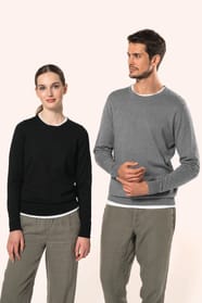 Jeune homme aux cheveux châtains courts et jeune femme aux cheveux châtains longs attachés en queue de cheval portent chacun un pull en coton Supima® col rond, reconnu pour la souplesse, la douceur et la durabilité de ses fibres extra-longues. Lui opte po