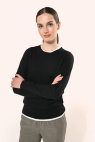 Jeune femme aux cheveux châtains longs attachés en queue de cheval portant un pull noir en coton Supima® col rond. Confectionné en fibres extra-longues, ce coton d’exception offre souplesse, douceur et durabilité. Sa maille révèle des points fantaisie obt