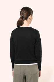 Jeune femme aux cheveux châtains longs attachés en queue de cheval portant un pull noir en coton Supima® col rond. Confectionné en fibres extra-longues, ce coton d’exception offre souplesse, douceur et durabilité. Sa maille révèle des points fantaisie obt