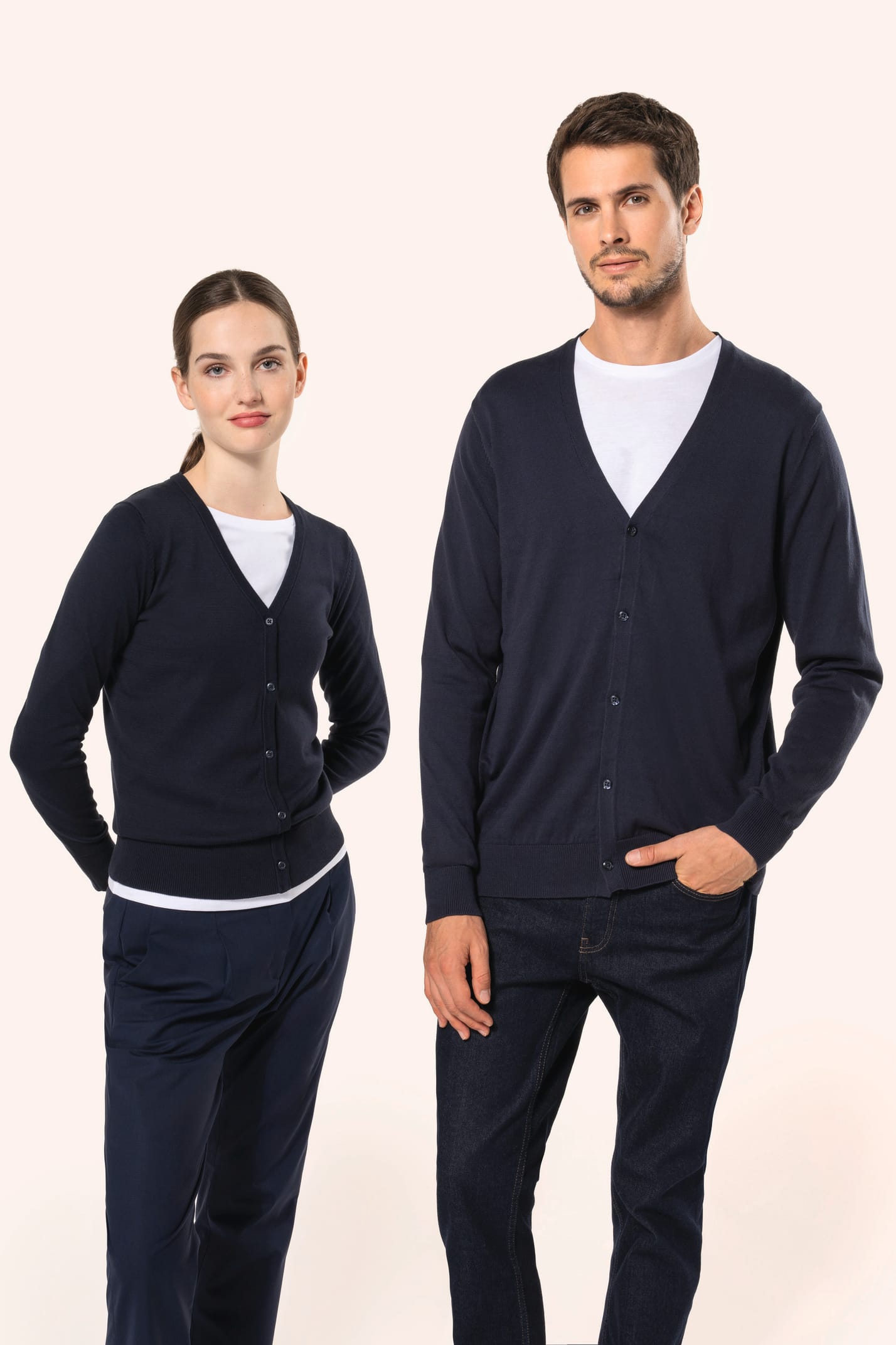 Jeune homme aux cheveux châtains courts et à la barbe naissante et jeune femme aux cheveux châtains longs attachés portent chacun un cardigan bleu profond en coton Supima®. Les fibres extra-longues de ce coton d’exception offrent souplesse, douceur et dur