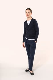 Jeune femme aux cheveux châtains longs attachés portant un cardigan bleu profond en coton Supima®. Ses fibres extra-longues apportent souplesse, douceur et durabilité à une maille de qualité supérieure. Confectionné en jauge 12 selon la technique fully-fa