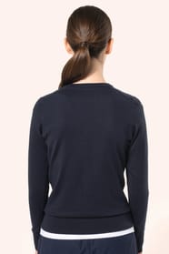 Jeune femme aux cheveux châtains longs attachés portant un cardigan bleu profond en coton Supima®. Ses fibres extra-longues apportent souplesse, douceur et durabilité à une maille de qualité supérieure. Confectionné en jauge 12 selon la technique fully-fa