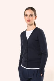 Jeune femme aux cheveux châtains longs attachés portant un cardigan bleu profond en coton Supima®. Ses fibres extra-longues apportent souplesse, douceur et durabilité à une maille de qualité supérieure. Confectionné en jauge 12 selon la technique fully-fa
