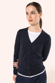 Jeune femme aux cheveux châtains longs attachés portant un cardigan bleu profond en coton Supima®. Ses fibres extra-longues apportent souplesse, douceur et durabilité à une maille de qualité supérieure. Confectionné en jauge 12 selon la technique fully-fa