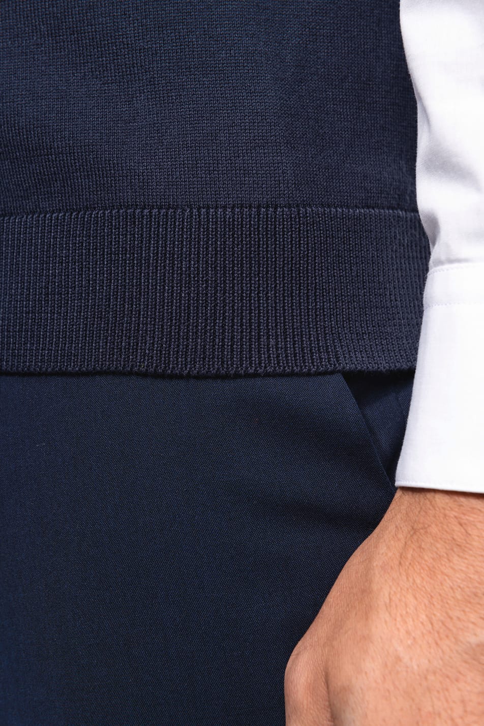 Détail bas du gilet bleu porté par un homme.