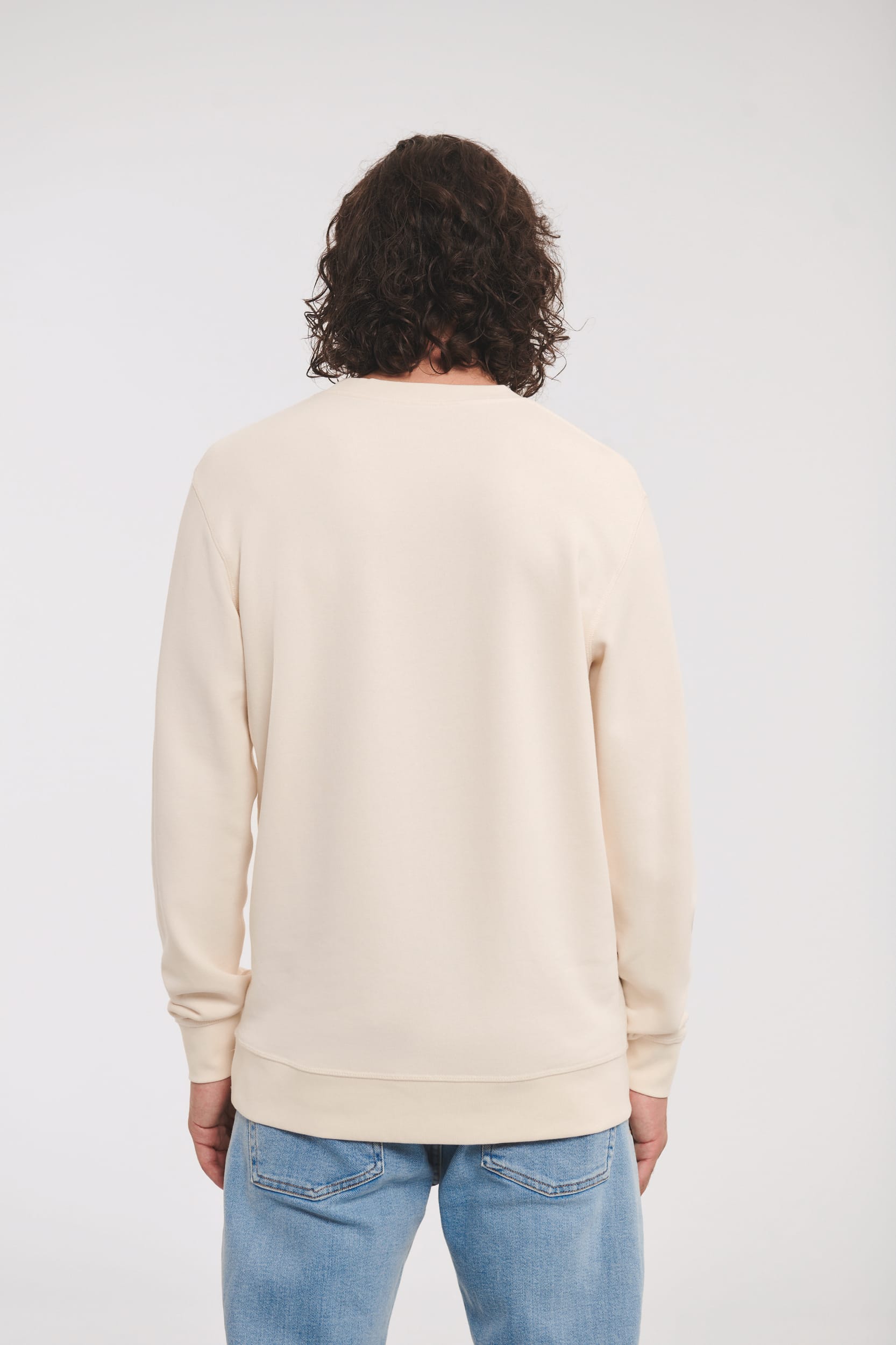 sweat-shirt beige col rond coupe droite porté par un homme vu de dos