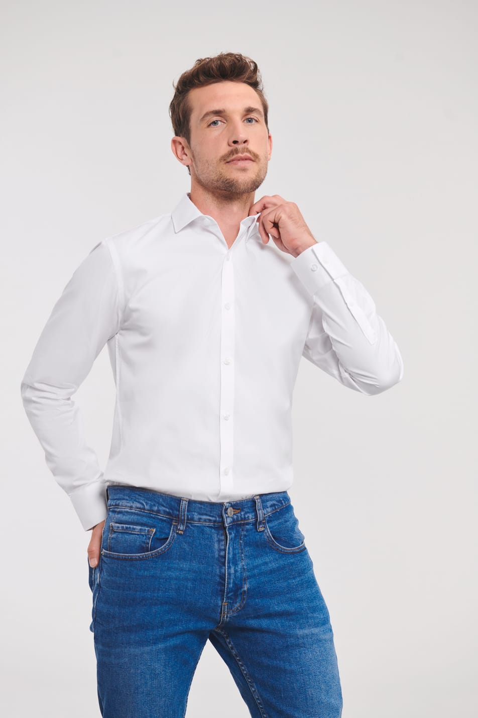 chemise blanche manches longues coupe ajustée col semi-évasé et rabat court portée rentrée dans un jean par un homme