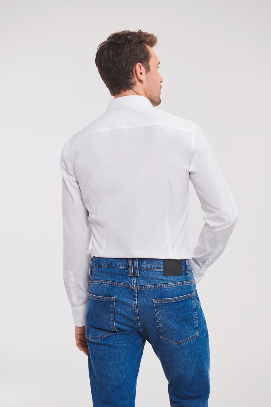 chemise blanche manches longues portée rentrée dans un jean par un homme vu de dos