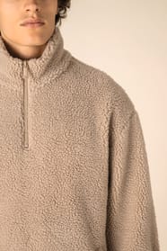 Détail épaule d'un sweat avec zip 1/4 en sherpa beige portée par un homme 