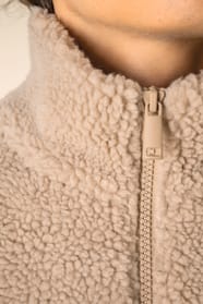 Détail du col d'un sweat 1/4 zip en sherpa beige porté par un homme